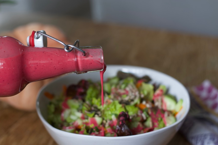 Cranberry Salad Dressing being poured over green salad.